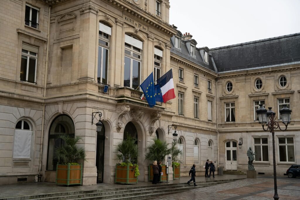 pexels-photo-29256197-29256197 Historic French building with EU and French flags in a serene courtyard setting.